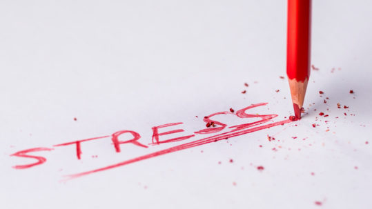 le mot stress écrit en rouge sur une feuille blanche avec appui très fort de la pointe du crayon sur la feuille